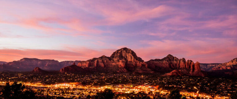 Desert sunset landscape with city lights underneath the mountains